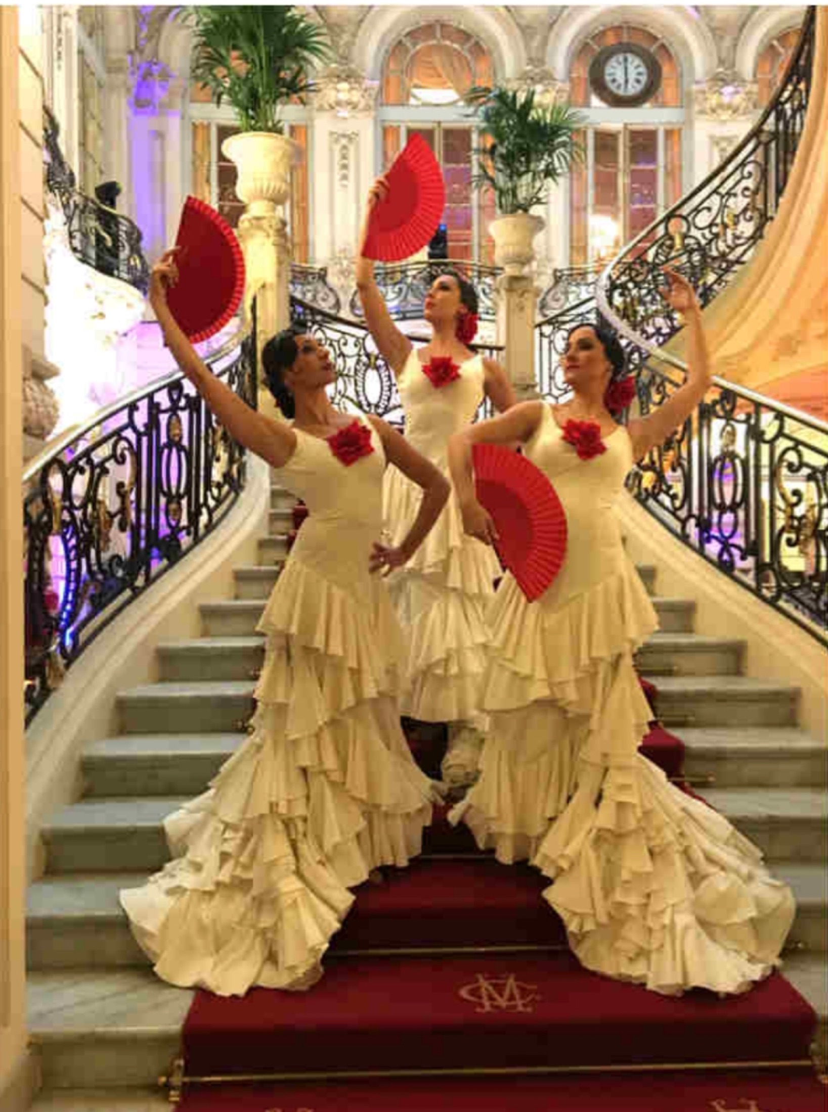 Tres bailaoras con abanicos rojos en una escalera.